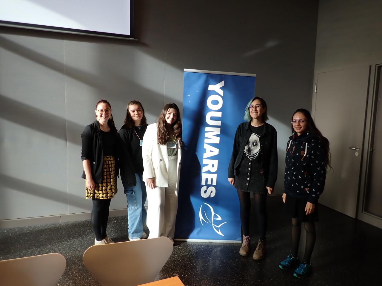 Image showing three panelists and two workshop organisers clustered around YOUMARES conference banner.